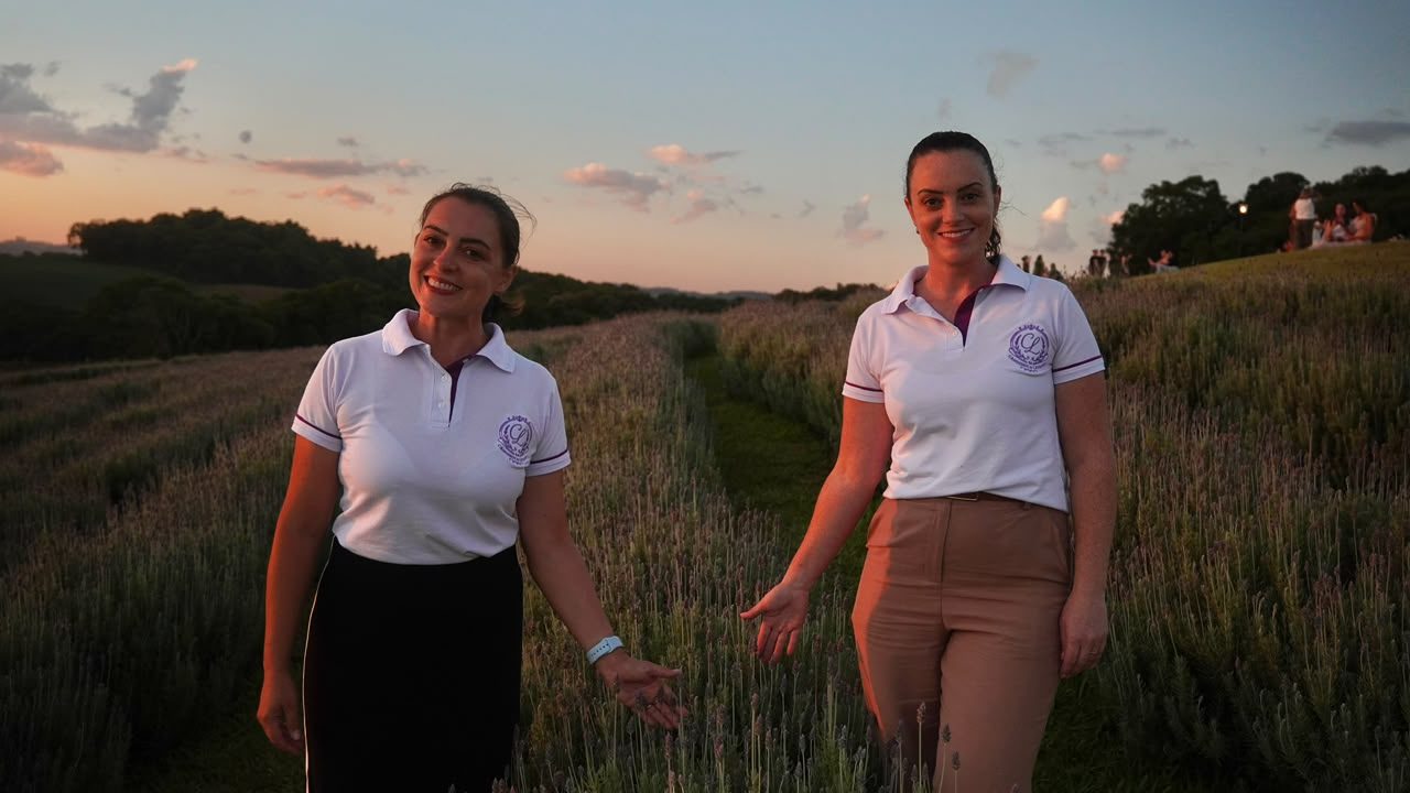 Clarice e Carolina Roy sorrindo entre as fileiras de lavanda ao entardecer